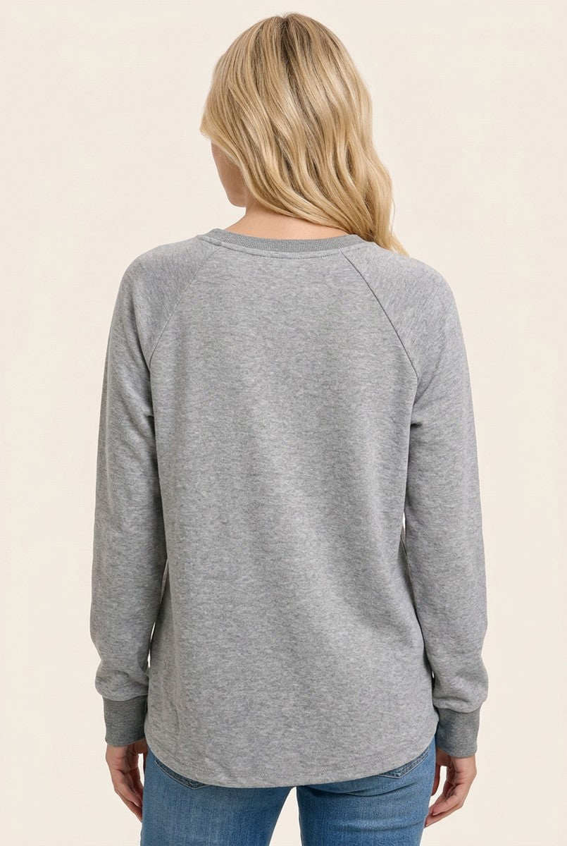 woman wearing a gray long sleeve sweatshirt, viewed from the back, paired with blue jeans