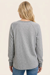 woman wearing a gray long sleeve sweatshirt, viewed from the back, paired with blue jeans