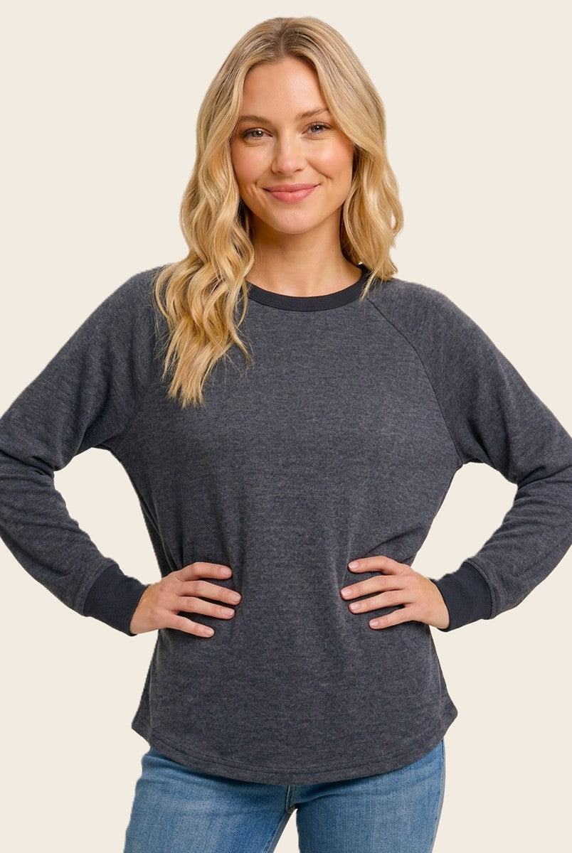 woman wearing a dark gray long sleeve raglan sweatshirt with navy blue trim and styled hair