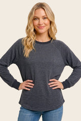 woman wearing a dark gray long sleeve raglan sweatshirt with navy blue trim and styled hair