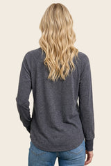 woman wearing a dark gray long sleeve top with a relaxed fit, seen from the back with wavy hair down