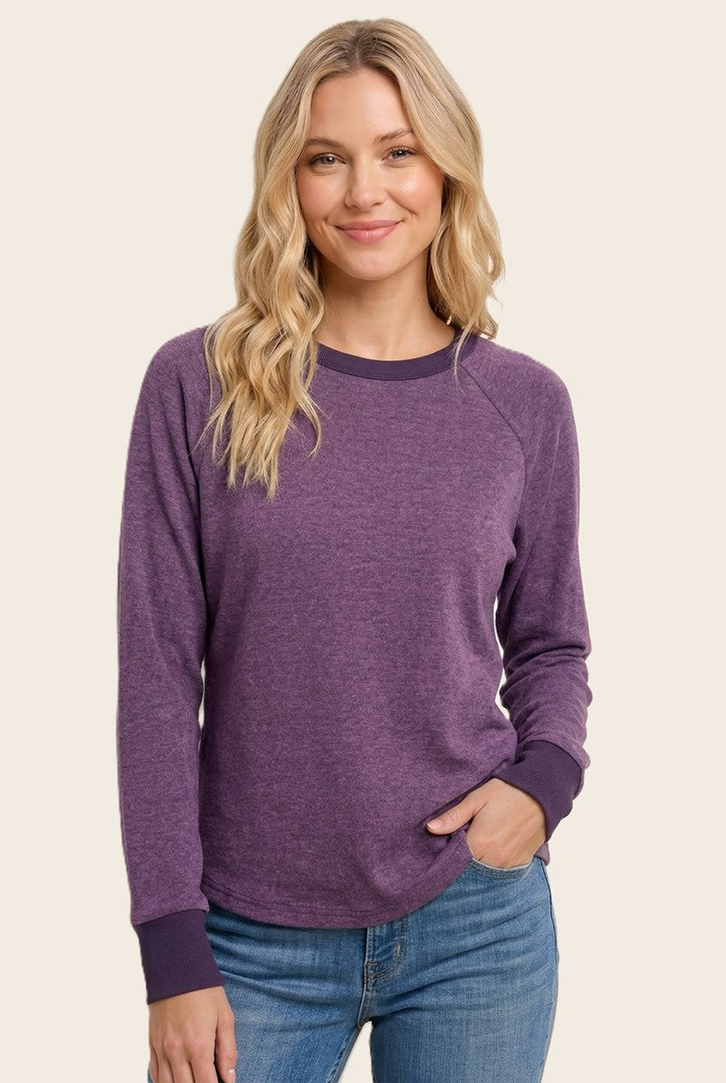 woman wearing a purple long sleeve sweatshirt with a relaxed fit and darker purple cuff details, smiling at the camera