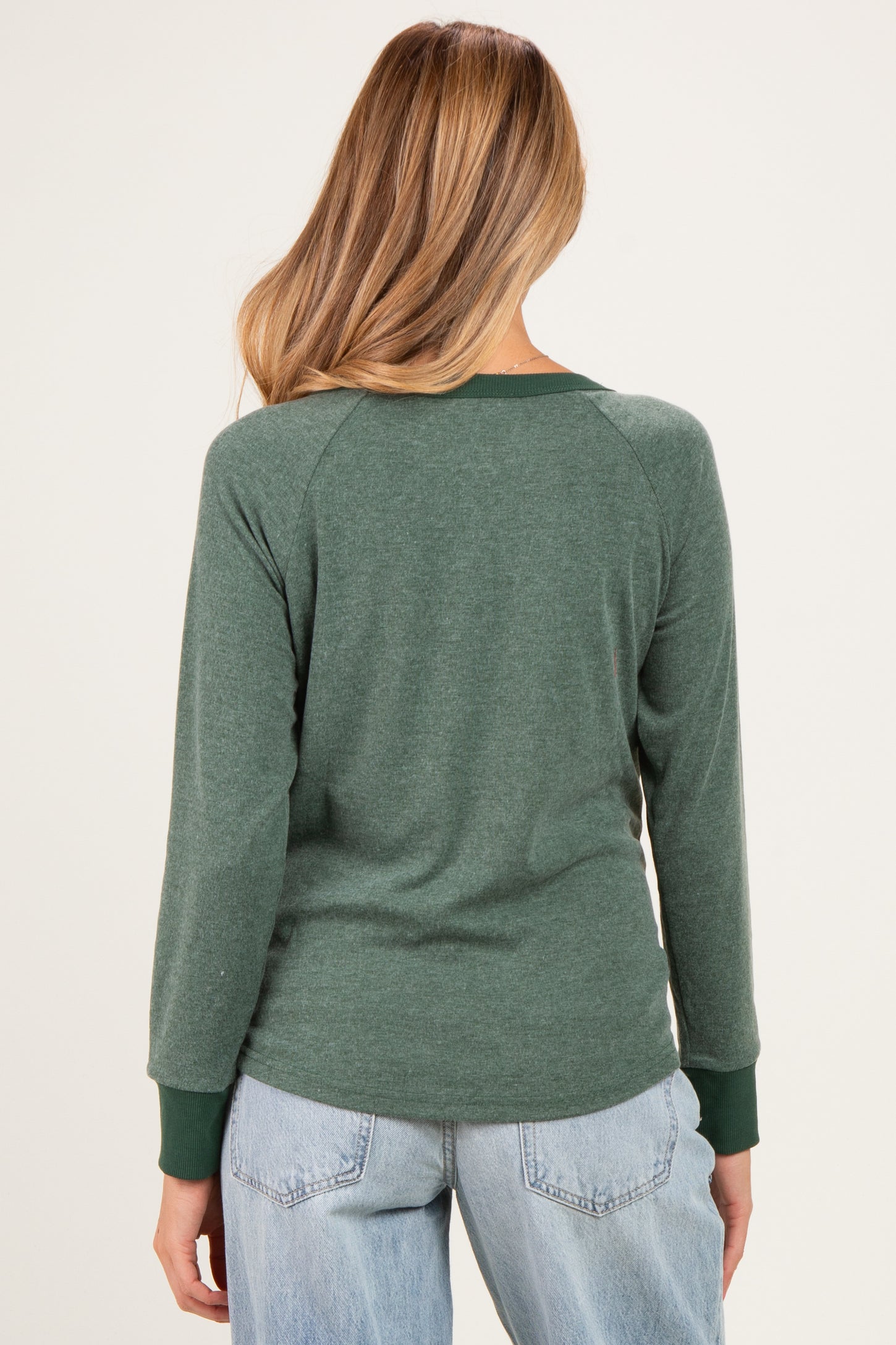 woman wearing a dark green maternity long sleeve top, shown from the back, with contrasting green cuffs and relaxed fit