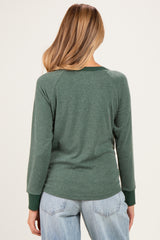 woman wearing a dark green maternity long sleeve top, shown from the back, with contrasting green cuffs and relaxed fit