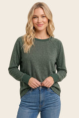 woman wearing a green long sleeve raglan sweatshirt with ribbed cuffs and a relaxed fit, paired with blue jeans