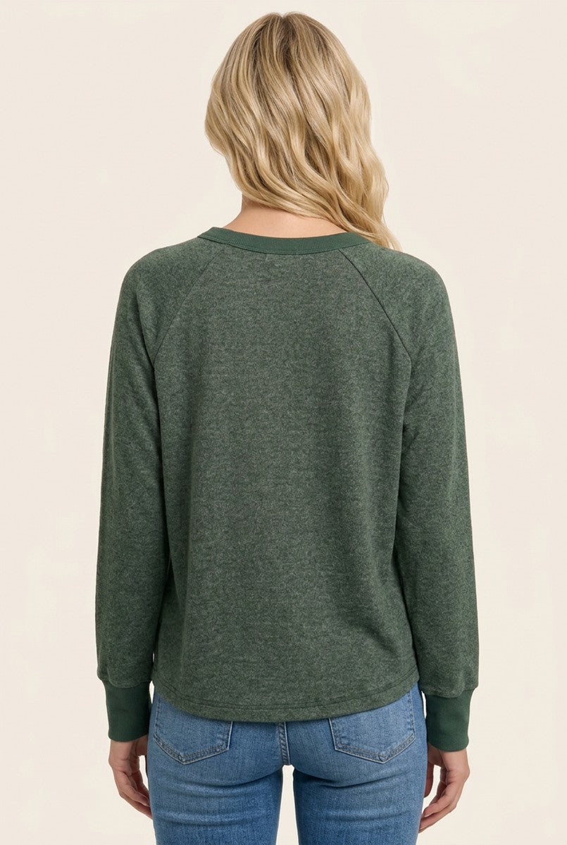 woman wearing a green long sleeve pullover top with raglan sleeves and a casual fit, viewed from the back