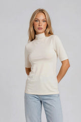 woman wearing a cream short sleeve mock neck top paired with light blue jeans