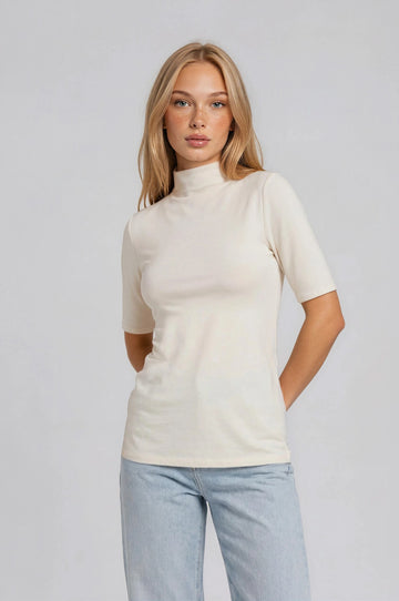 woman wearing a cream short sleeve mock neck top paired with light blue jeans