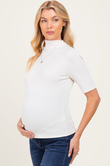 woman wearing a white short sleeve maternity top and holding her baby bump