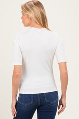 woman wearing a white short sleeve maternity top, seen from the back, paired with blue jeans