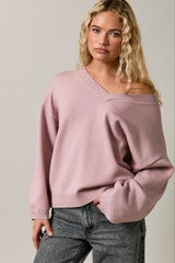 woman wearing a pink off-shoulder oversized sweater paired with gray jeans