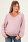 woman wearing a light pink v-neck maternity sweater with bell sleeves and a visible baby bump
