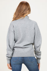 woman wearing a gray maternity sweater with a turtleneck and relaxed fit, seen from the back