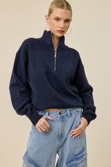 woman wearing a navy blue half-zip pullover sweater with balloon sleeves and high-waisted denim wide-leg jeans