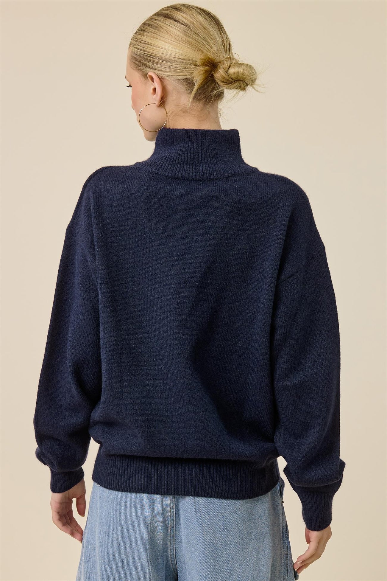 woman wearing a dark navy oversized turtleneck sweater with loose sleeves and a ribbed hem
