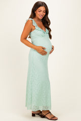 woman wearing a mint green lace maternity dress with ruffled straps and holding her baby bump