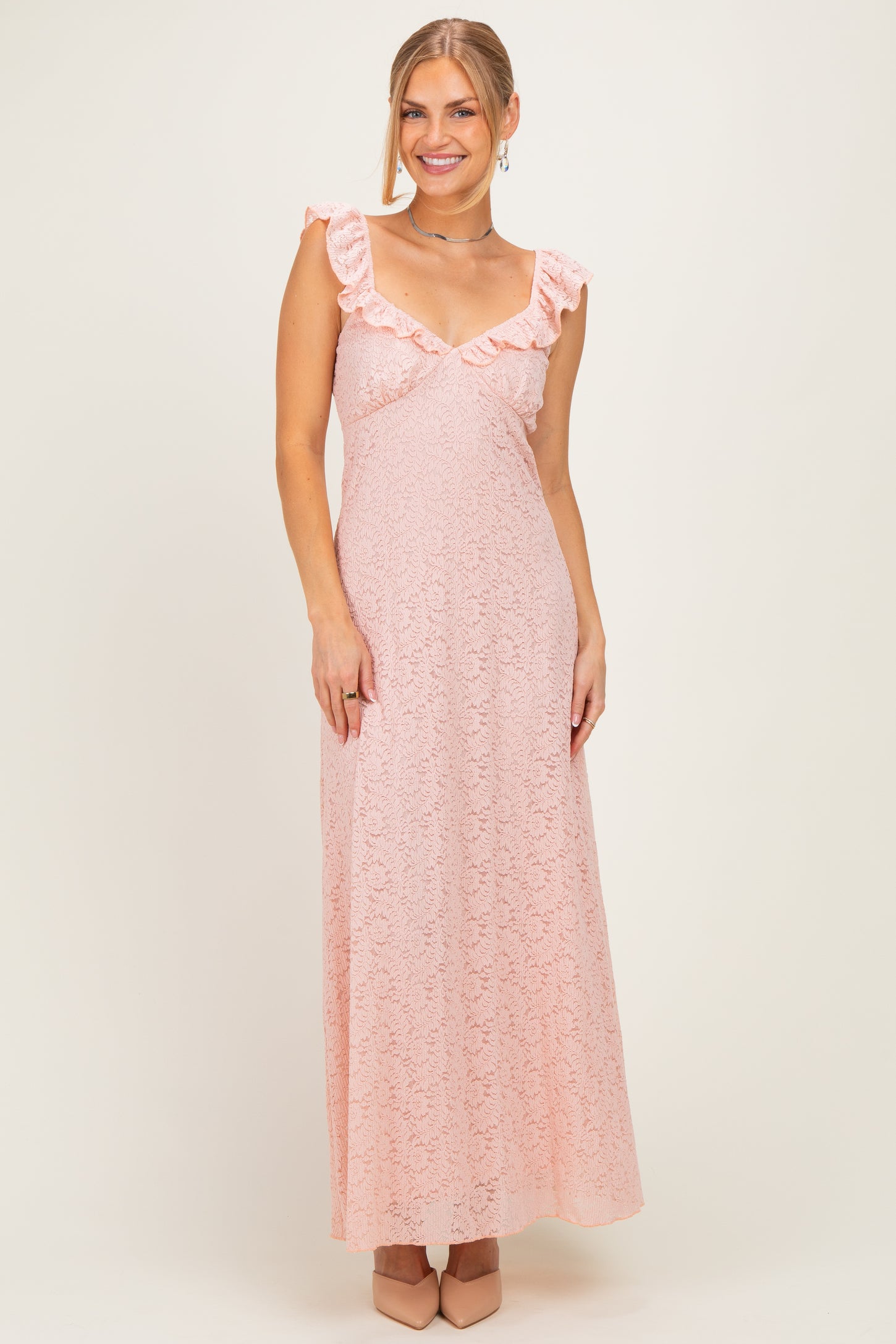 woman wearing a blush pink maxi dress with ruffle detail on the sleeves and lace texture