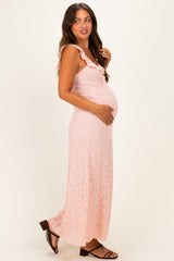 woman wearing a light pink lace maternity maxi dress and holding her baby bump