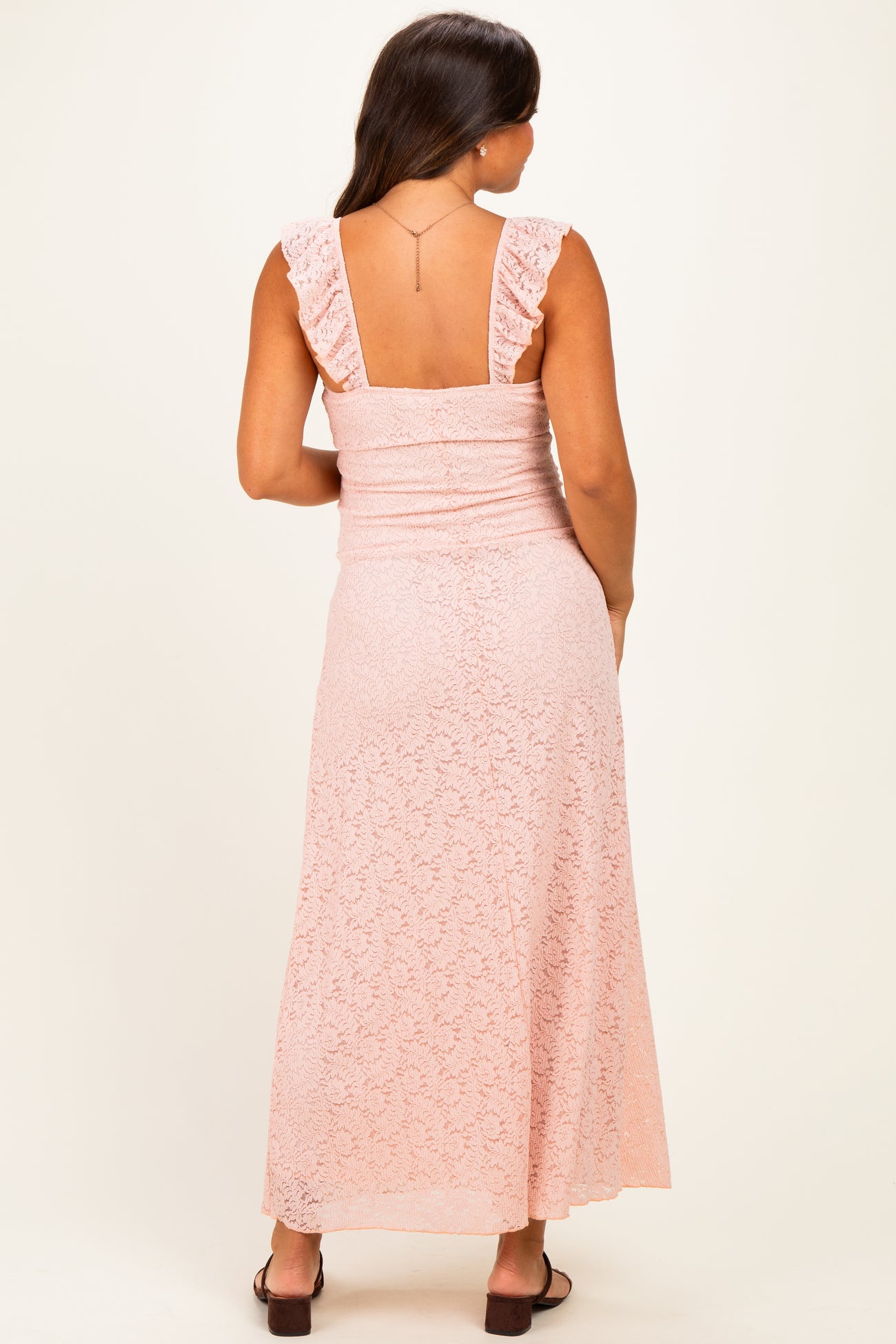 woman wearing a pink lace maternity maxi dress with ruffled straps, showing the back view