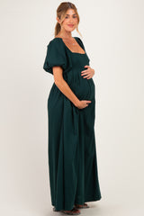 woman wearing a dark green short sleeve maternity dress holding her baby bump