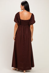 woman wearing a brown maxi dress with puff sleeves and a smocked back, viewed from the back