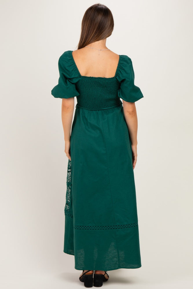 woman wearing a dark green maternity maxi dress with short puff sleeves and a smocked back design