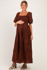 woman wearing a brown puff sleeve maxi dress with smocked bodice, holding her baby bump