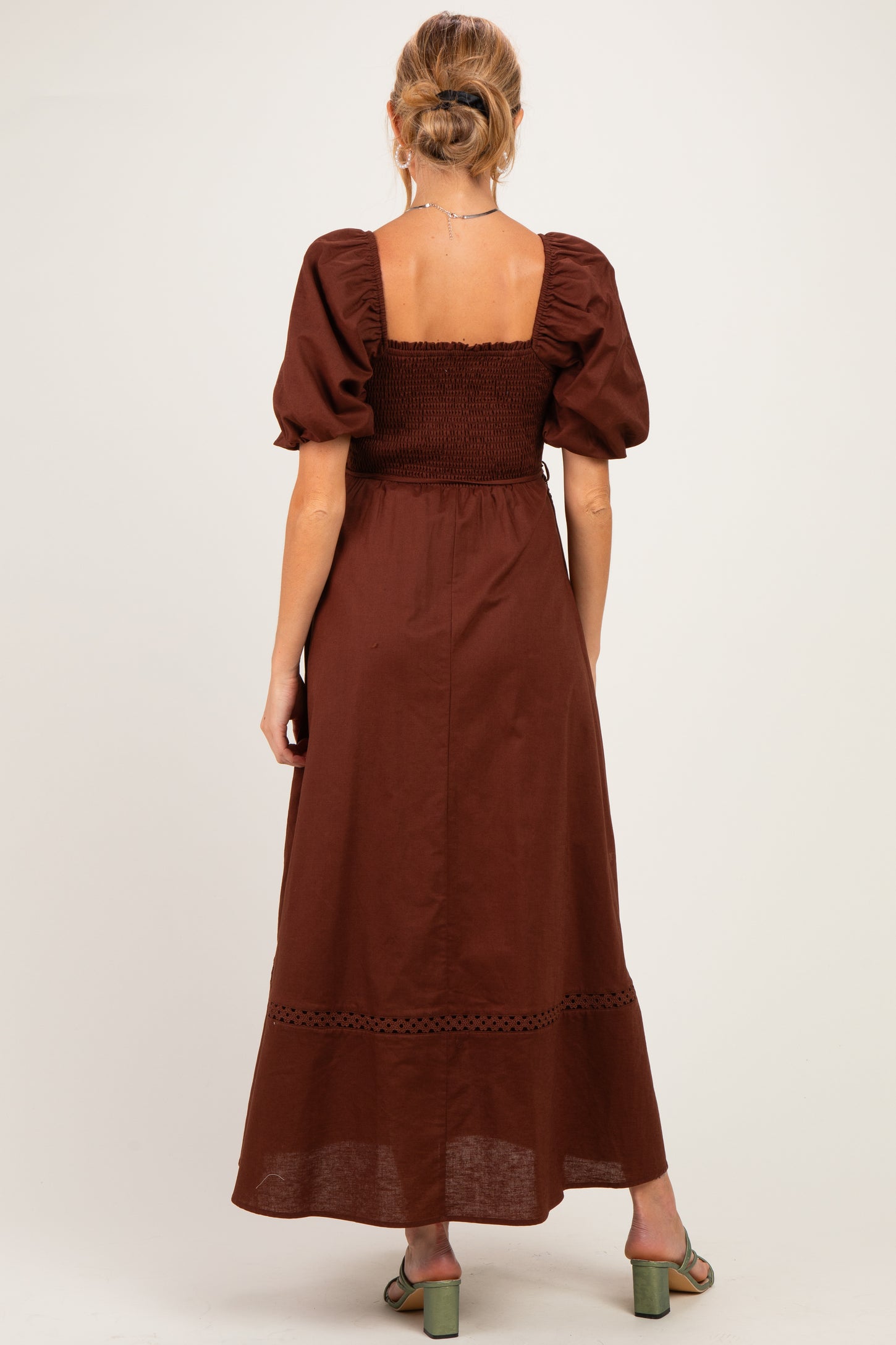 woman wearing a brown maternity maxi dress with puff sleeves and smocked bodice, showing the back view