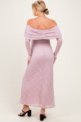 woman wearing a blush pink off-shoulder lace maternity dress with long sleeves and a fitted silhouette