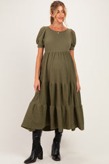 woman wearing an olive green tiered maternity dress with puff sleeves and a baby bump visible