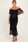 woman wearing a black off-the-shoulder lace maternity dress with flutter sleeves and a fitted silhouette, showcasing her baby bump