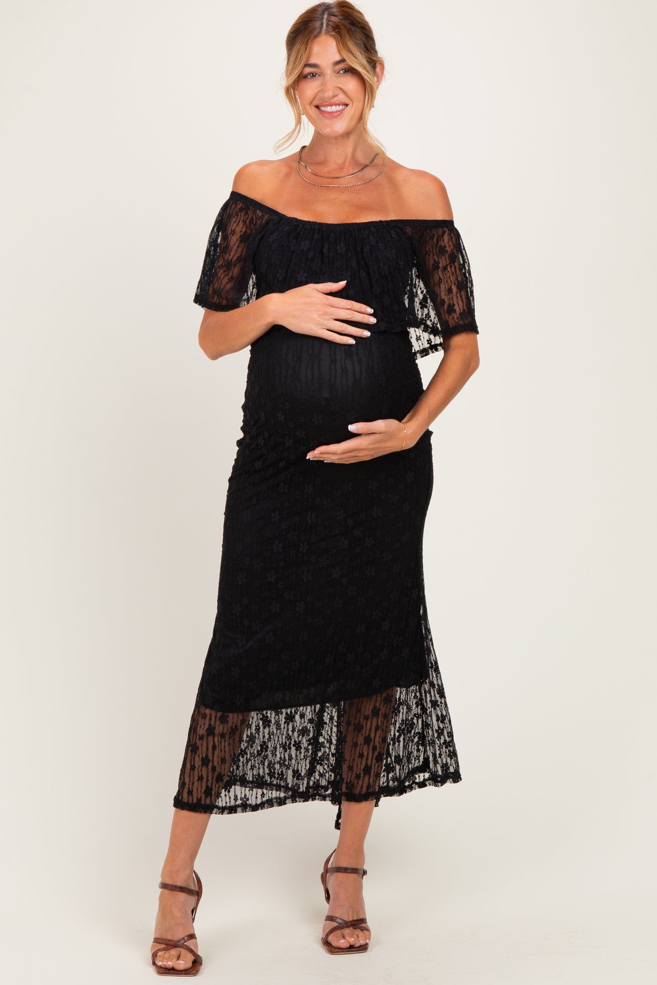 woman wearing a black off-the-shoulder maternity dress with lace detailing and a baby bump visible