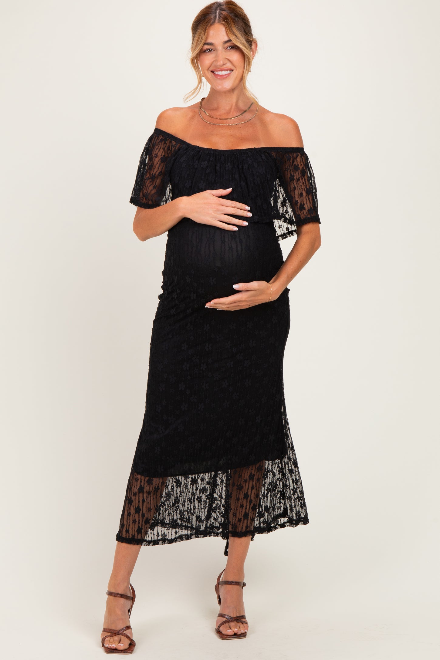 woman wearing a black off-the-shoulder maternity dress with lace detailing and a baby bump visible