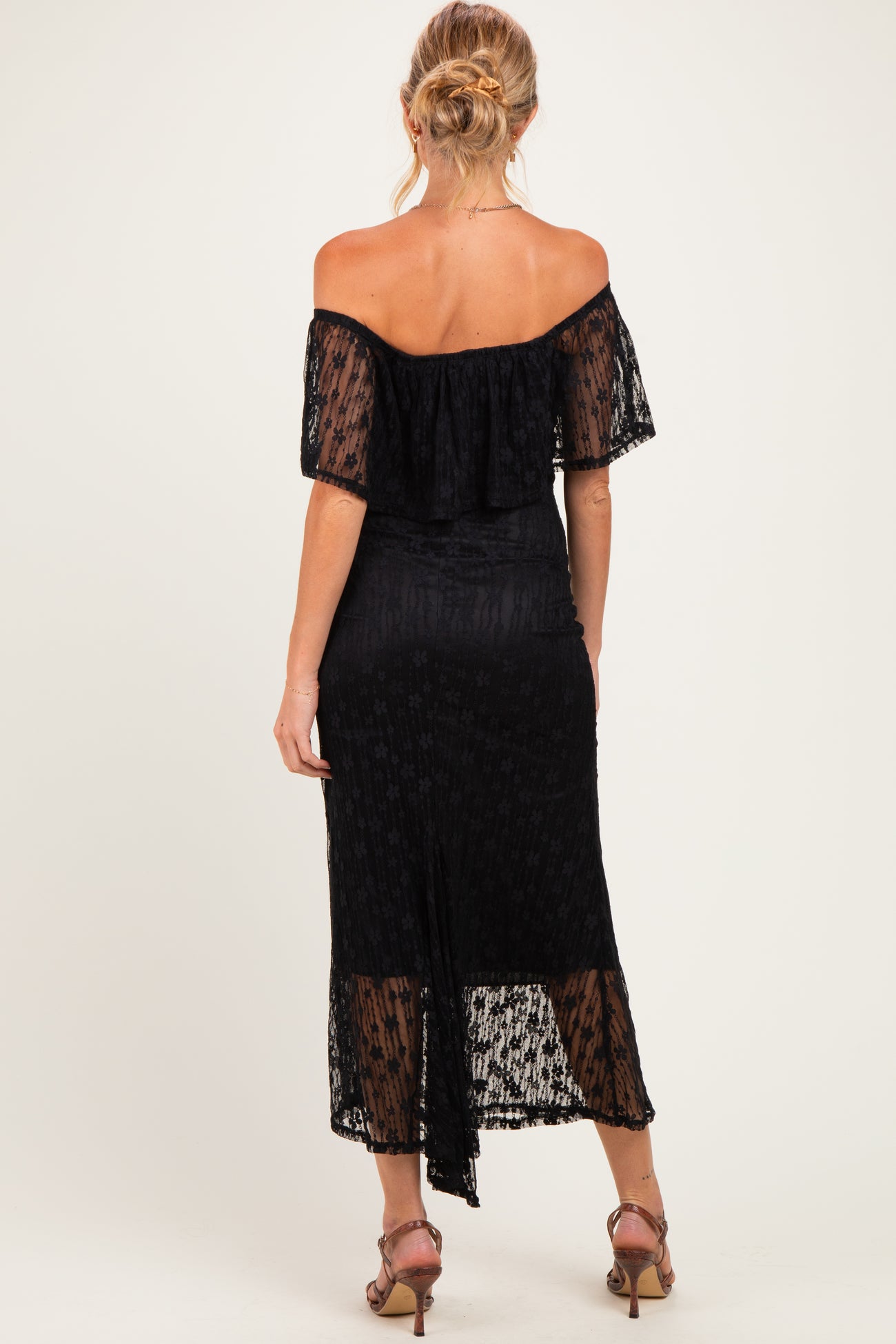 woman wearing a black off-the-shoulder maternity dress with a flowy design and a mid-length hemline