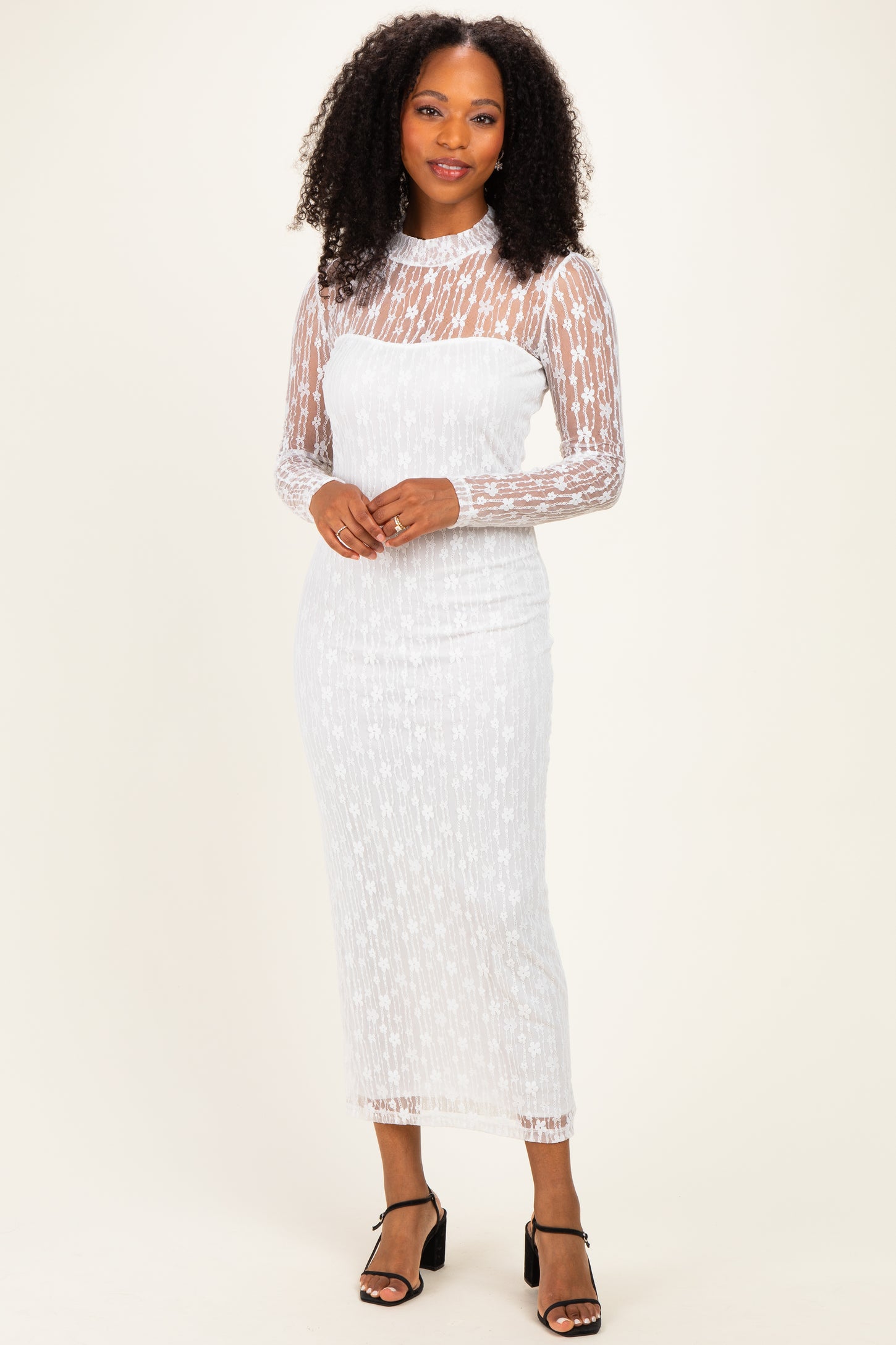 woman wearing a white lace long sleeve midi dress with a fitted silhouette and sheer details