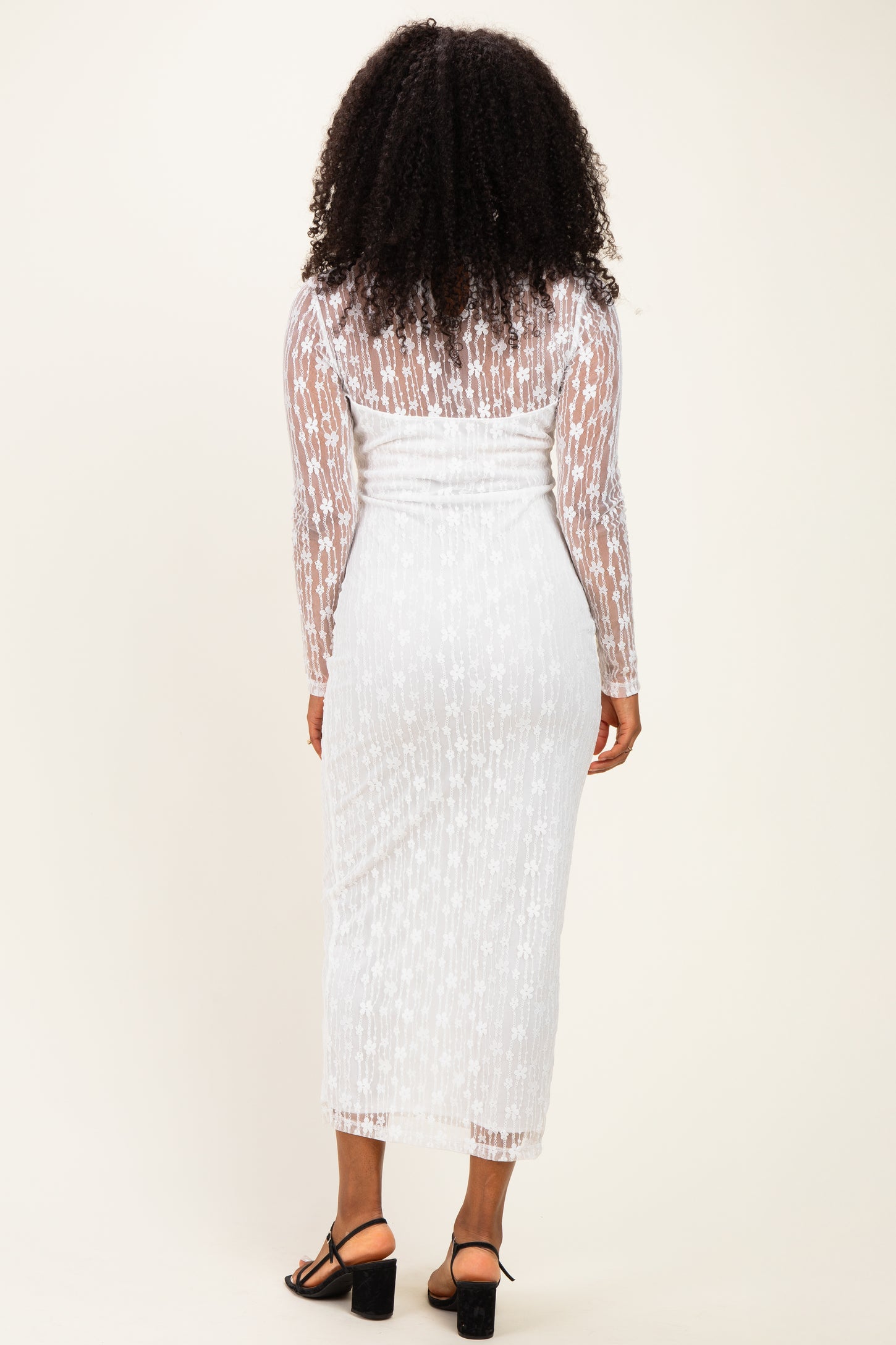 woman wearing a white long sleeve star-patterned dress with a fitted silhouette and a sheer overlay