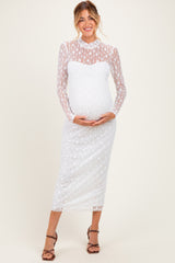 woman wearing a white lace long sleeve maternity dress and holding her baby bump