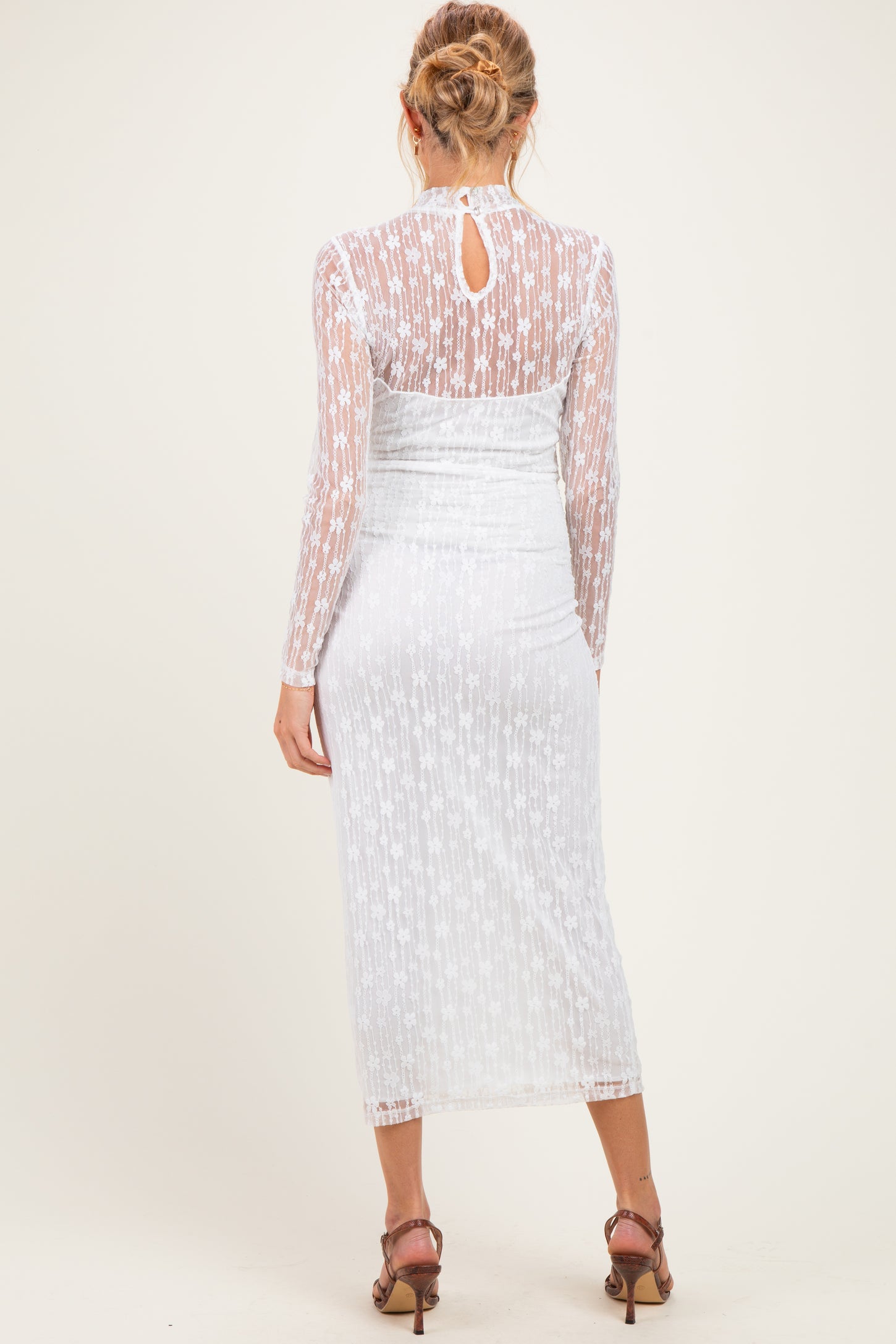 woman wearing a sheer white maternity dress with long sleeves and a bodycon fit, showing a baby bump from the back