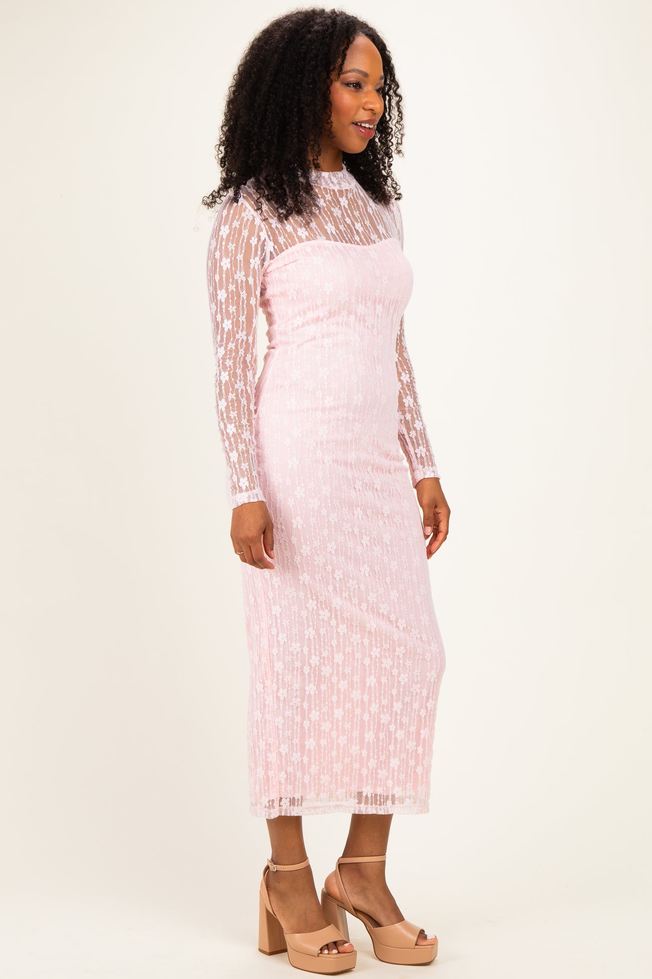 woman wearing a pink long sleeve lace dress with star patterns and a fitted style, paired with beige block-heeled sandals