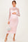 woman wearing a light pink long sleeve lace maternity dress and holding her baby bump with a white handbag