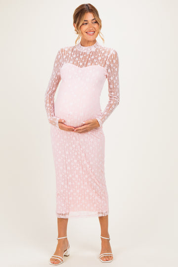 woman wearing a pink lace long sleeve maternity dress and holding her baby bump