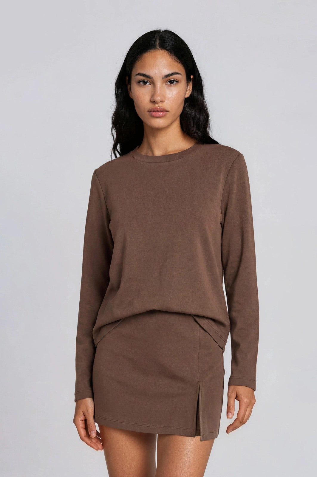 woman wearing a brown long sleeve top with a matching mini skirt and side slit