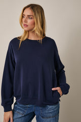 woman wearing a navy oversized sweatshirt with a round neckline and a front pocket, styled with casual jeans