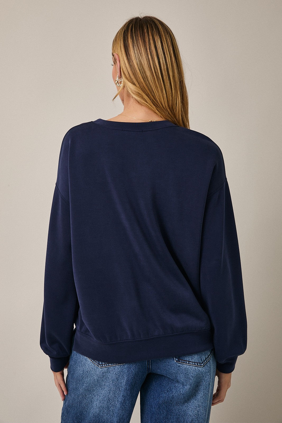 woman wearing a dark navy oversized sweatshirt with long sleeves and relaxed fit, viewed from the back