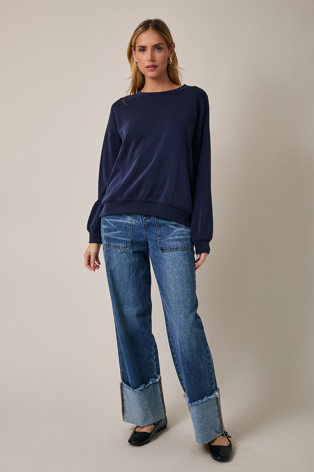 woman wearing a navy blue long sleeve sweater paired with distressed wide-leg jeans and black flats