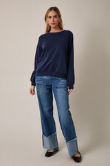 woman wearing a navy blue long sleeve sweater paired with distressed wide-leg jeans and black flats