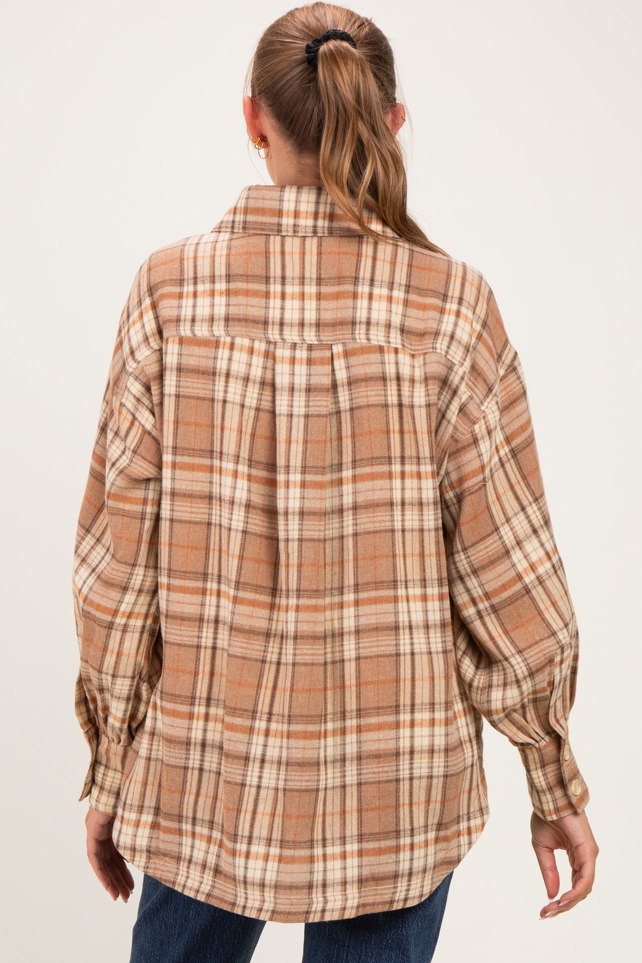 woman wearing a brown and cream plaid maternity flannel shirt, showing the back view with a relaxed fit