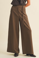 woman wearing wide-leg brown trousers with a high waist and front tie detail