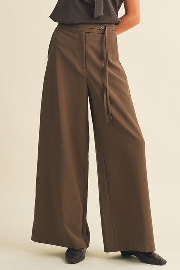 woman wearing wide-leg brown trousers with a high waist and front tie detail