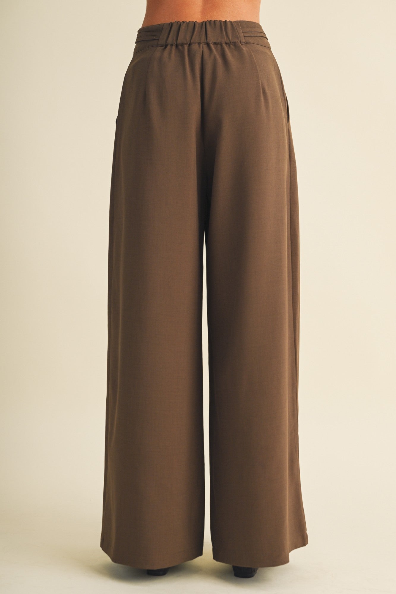 woman wearing brown wide-leg trousers with an elastic waistband and side pockets